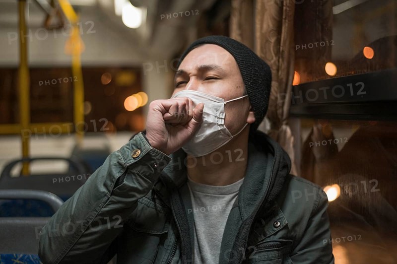 Front view sick man coughing bus while wearing medical mask