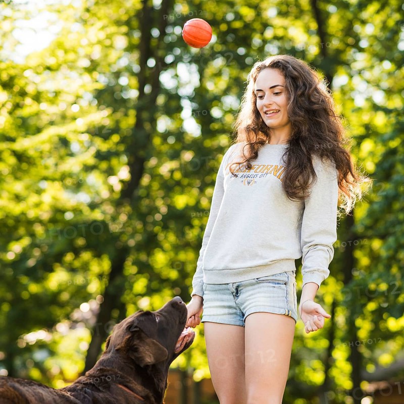 Young woman throwing ball her dog park