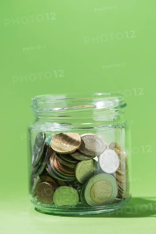 Close up coins inside glass container green background