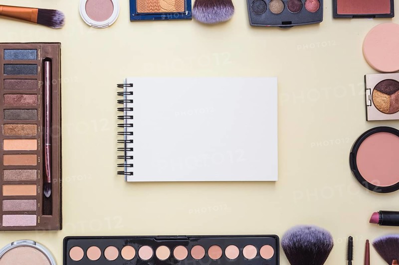 Overhead view spiral blank notepad surrounded with cosmetics product