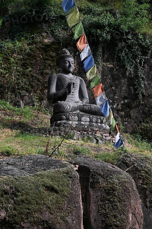 Buddha statue and Tibetan prayer flags in front of the entrance to the Messner Mountain Museum near Bolzano
