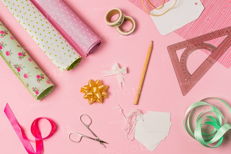 High angle view stationery supplies with gift wrap tags pink background