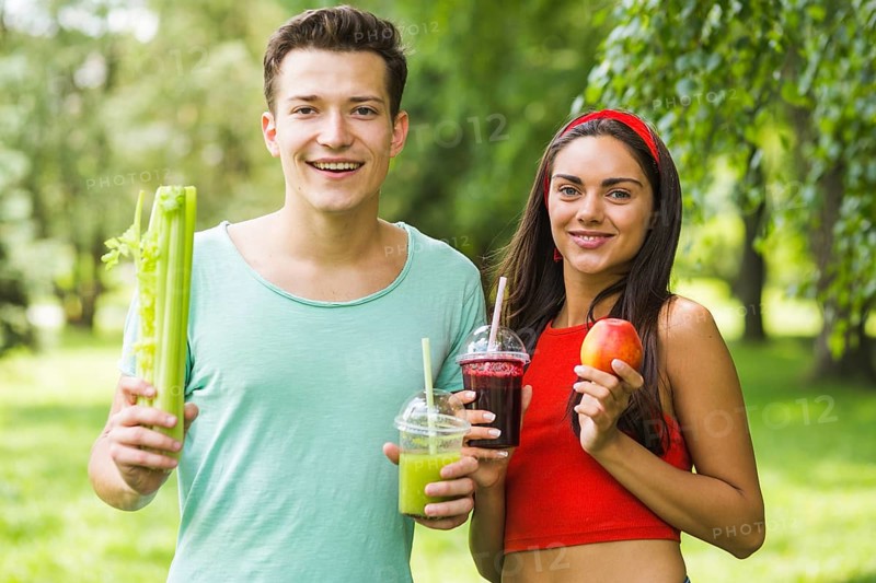 Smiling couple holding avocado apple smoothies hand