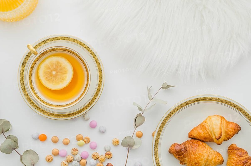 Fur baked croissant candies ginger lemon tea cup white background