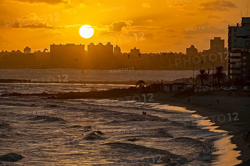 Sandy beach and surfers surfing at sunset near the city Montevideo