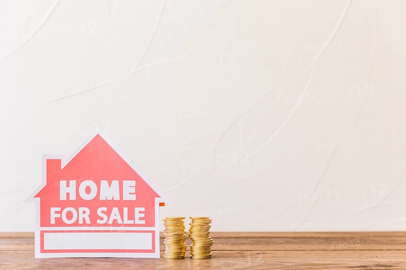 Home sale icon with stacked coins wooden desk