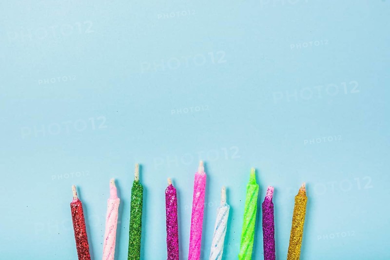 Row colorful sparkling candles blue backdrop