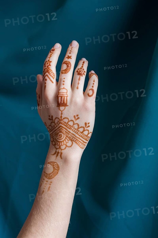 Woman hand with mehndi near blue textile