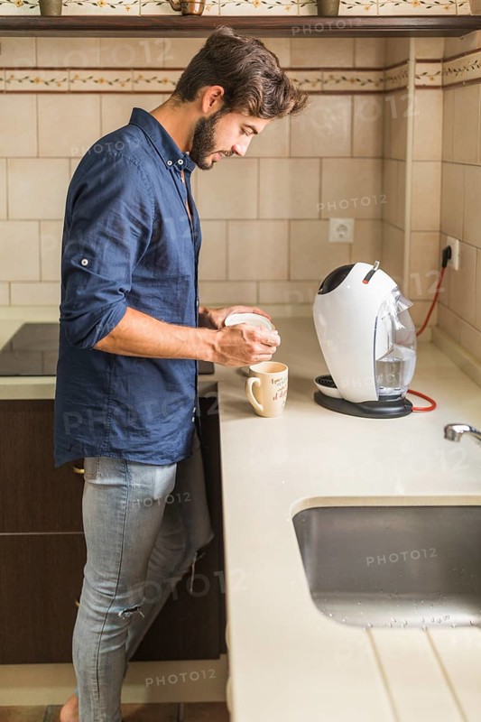 Young man standing kitchen preparing coffee