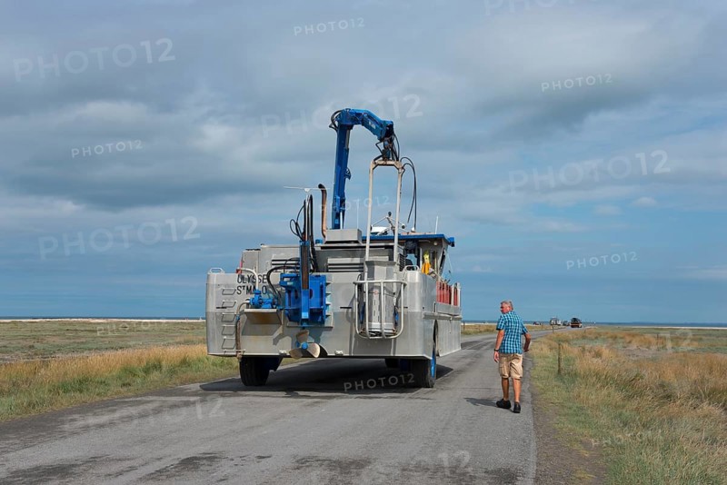 Man walking beside an amphibious vehicle on the road