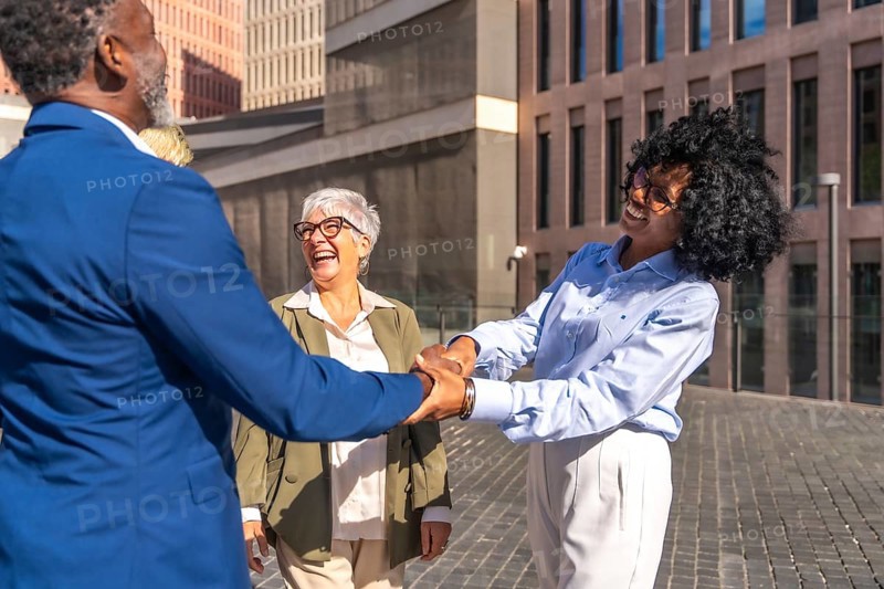African business people shaking hands when they meet outdoors next to other people