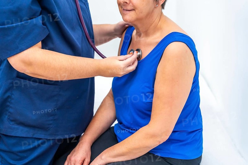 Cardiologist listening to the heartbeats of an older woman using a stethoscope