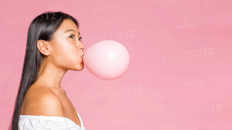 Sideways woman inflates pink balloon