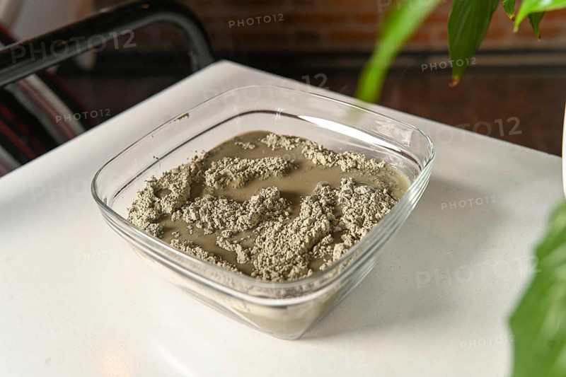 Masseuse preparing mixing clay and water for anti inflammatory massage in spa center
