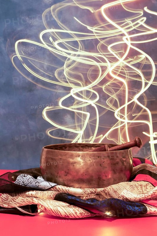 Tibetan singing bowl on colored cloth with moving led lights in the background