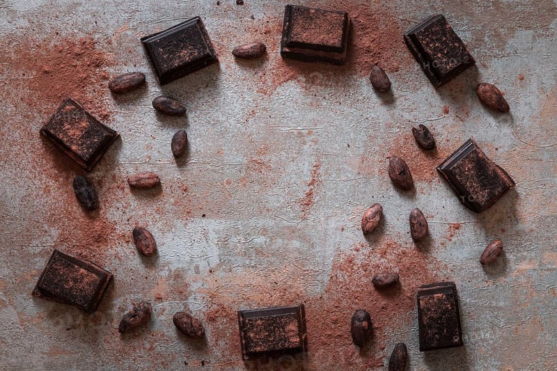Overhead view broken chocolate bas with cocoa powder raw beans