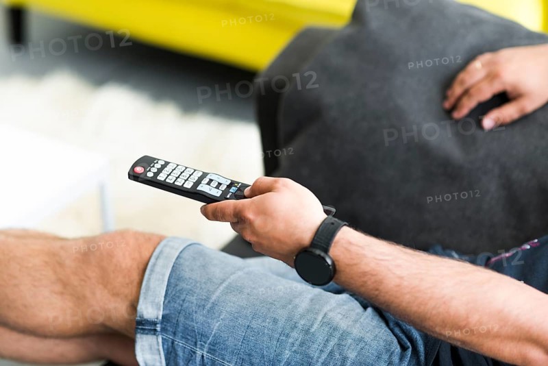 Close up man s hand holding television remote control