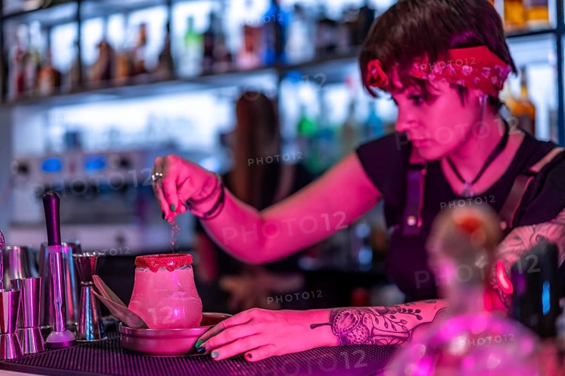 Bartender garnishing the top of a margarita cocktail in a bar