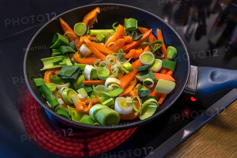 Fresh vegetables in a pan on a red-hot hob