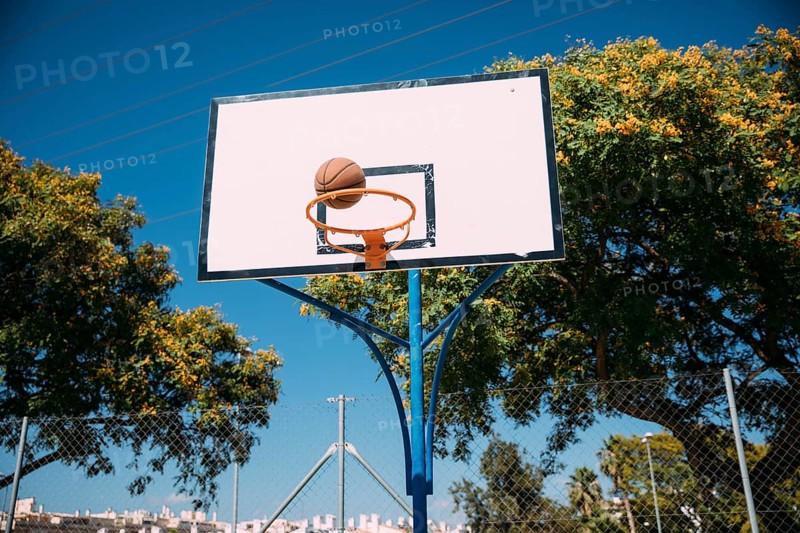 Basketball falling into hoop blue sky