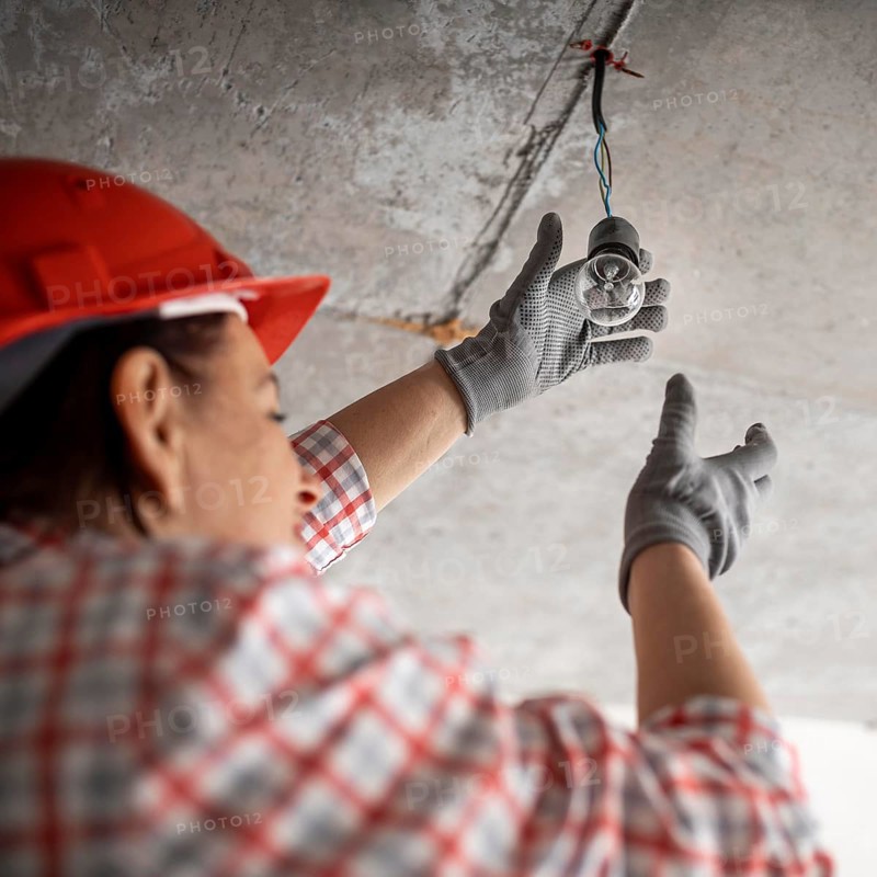 Low angle female construction worker with light bulb