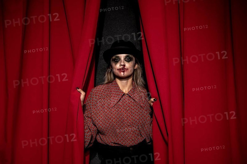 Make up woman holding red theatre curtain
