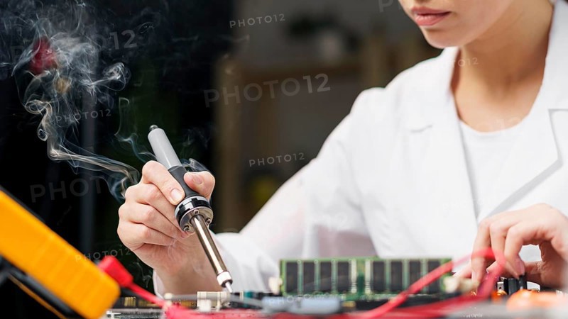 Female technician with soldering iron electronics board