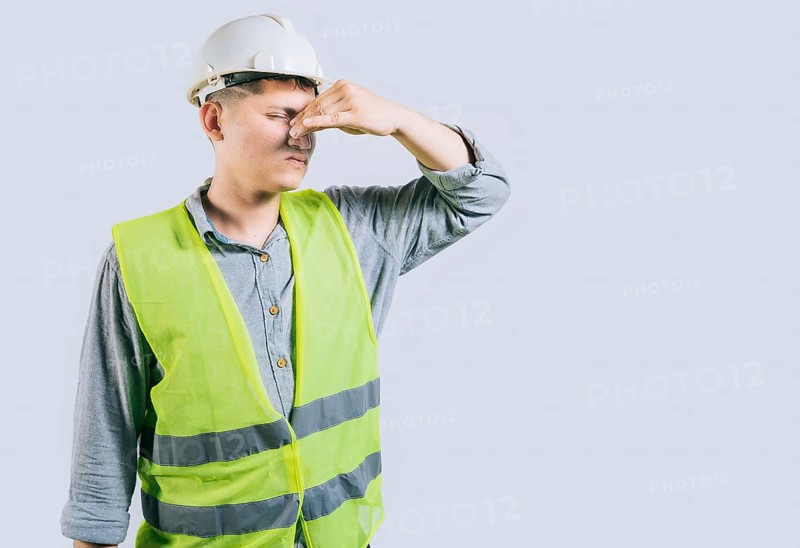 Man engineer covering her nose from a bad smell isolated isolated. Displeased young engineer holding her nose isolated
