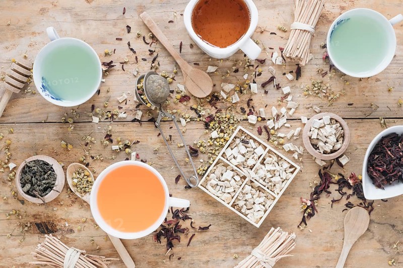 Different types tea ceramic cup with herbs honey dipper