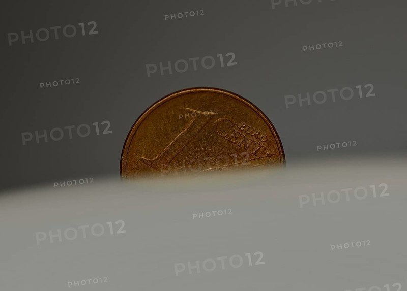 A 1 cent coin as a macro shot in the slot of a piggy bank