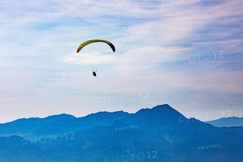 Paragliders high above the mountains with a view of the Klagenfurt basin and the Karawanken