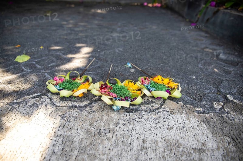 Three beautiful colourful opera bowls on the roadside. Flowers as an offering in Ubud