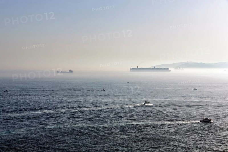 Cargo ships and motorboats in the haze