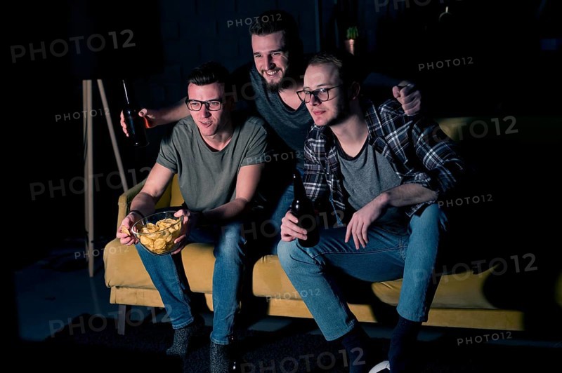 Male friends watching sports tv together with snacks
