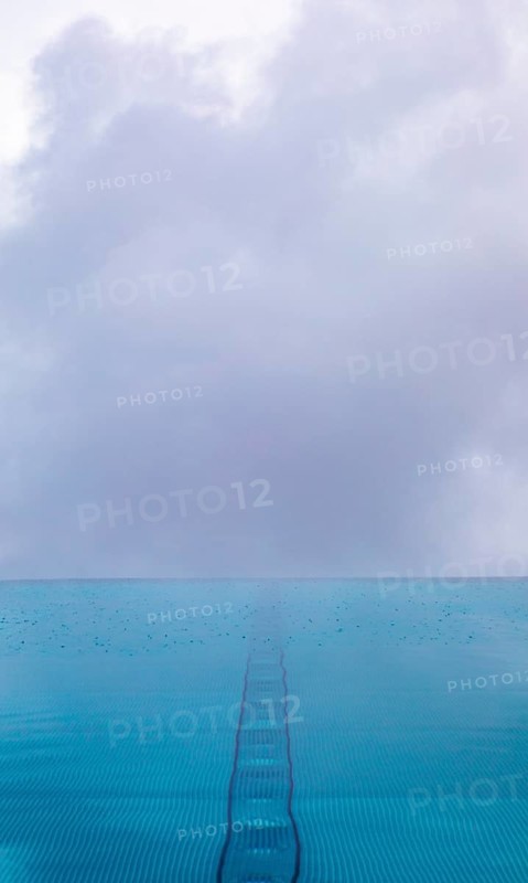 Rippled water surface during rain in swimming pool with dramatic cloudy sky