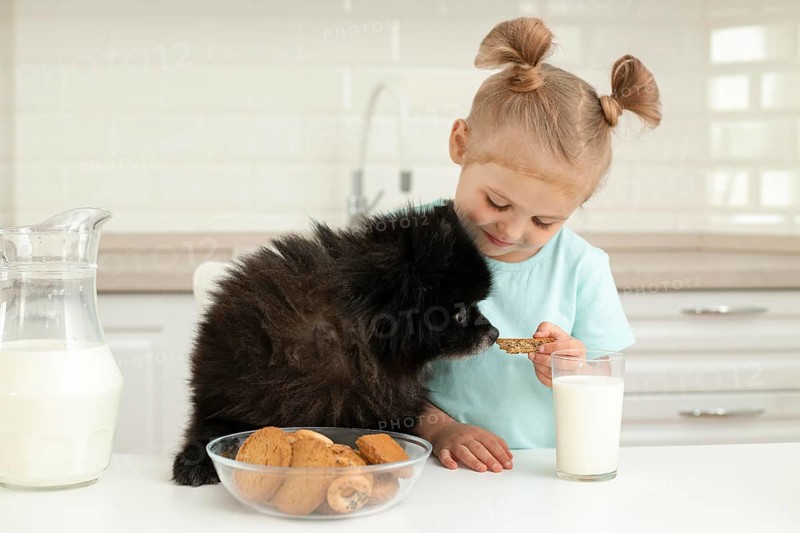 Girl drinking milk playing with dog home