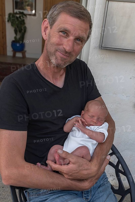 Young grandpa with his newborn grandson in his arms