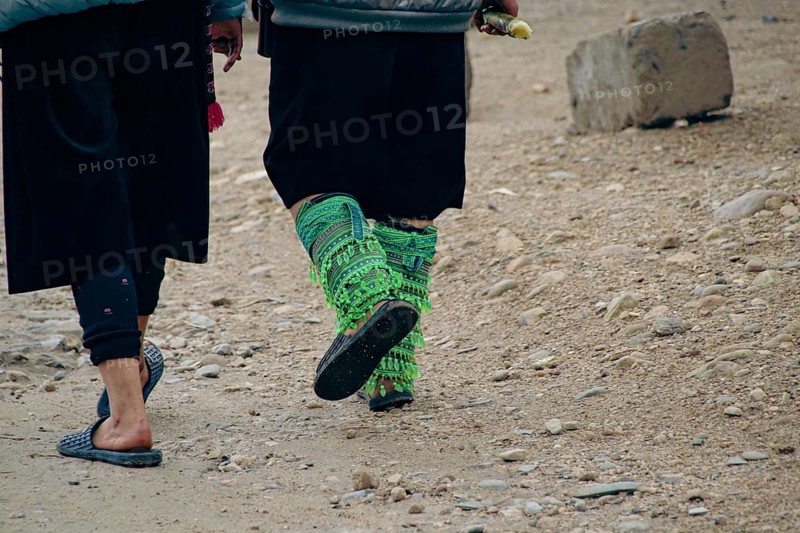 Close up to two black hmong women walking and wearing their ethnic leg ornaments