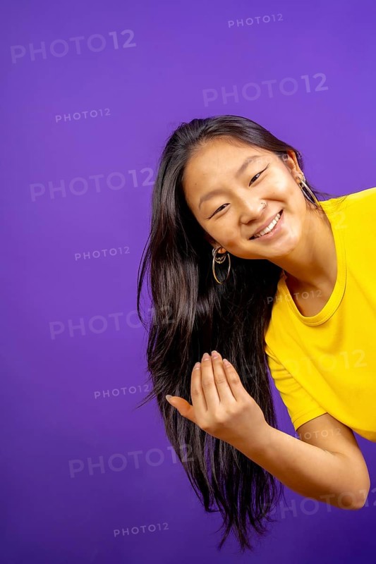 Vertical studio photo with purple background of chinese woman inviting to join with hand