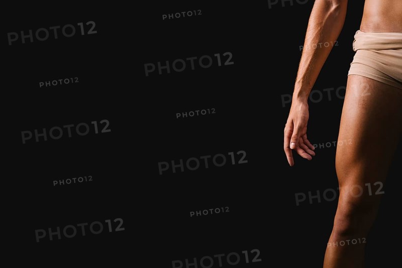 Athletic naked male standing against black background