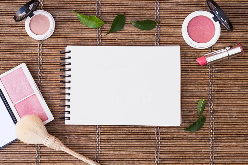 Blank spiral notepad surrounded with cosmetics products placemat