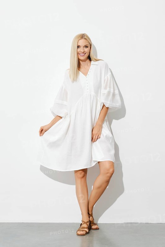 Portrait of happy stylish woman in white sundress indoors