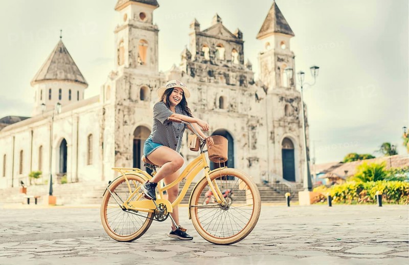 Happy girl in hat riding a bicycle at sunset. Tourism and travel concept. Lifestyle of a happy girl in hat on bicycle on the street. Granada