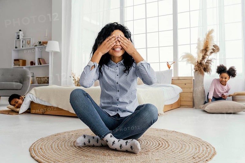 Front view smiley mother playing hide seek home with her children