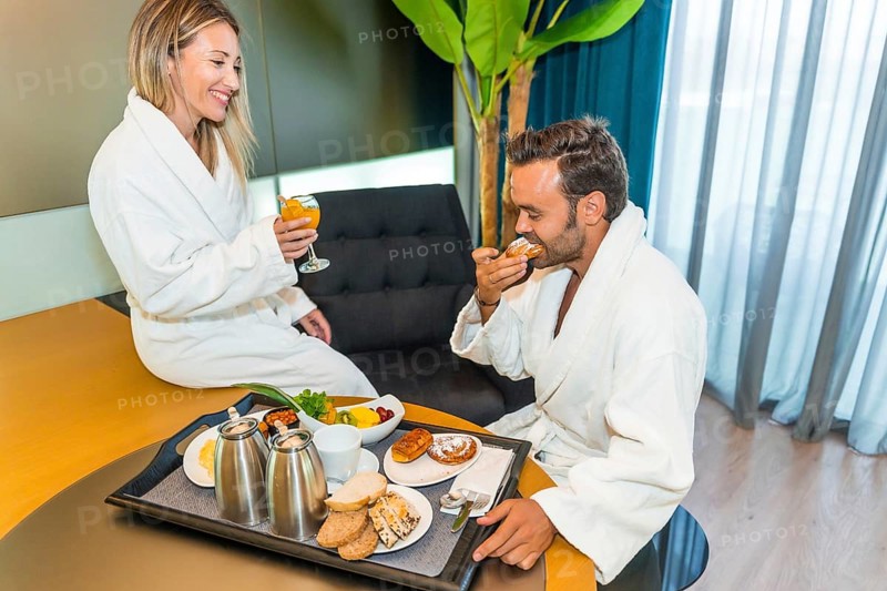 Couple in bathrobe enjoying delicious breakfast in a luxury hotel room