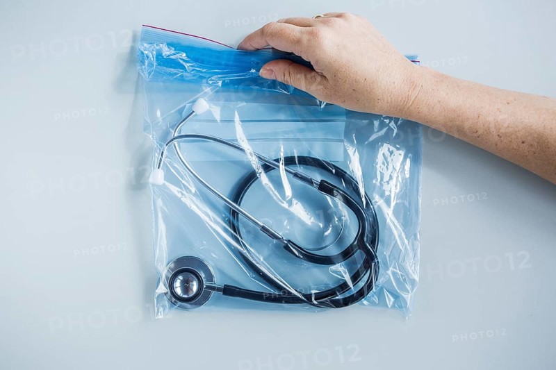 Human hand holding zip lock plastic bag with stethoscope