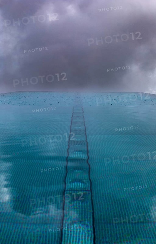 Rippled water surface during rain in swimming pool with dramatic cloudy sky