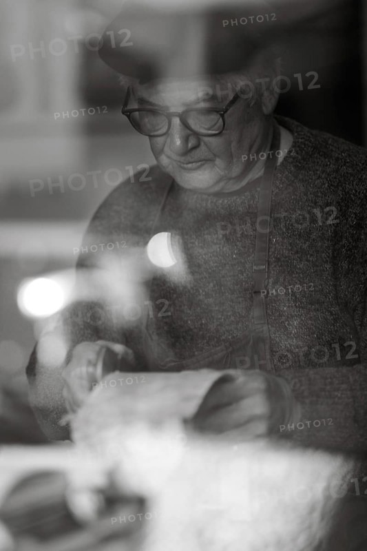 Senior expert luthier artisan violin maker carve sculpt chisel ribs of a new classical model cello in workshop Cremona Italy