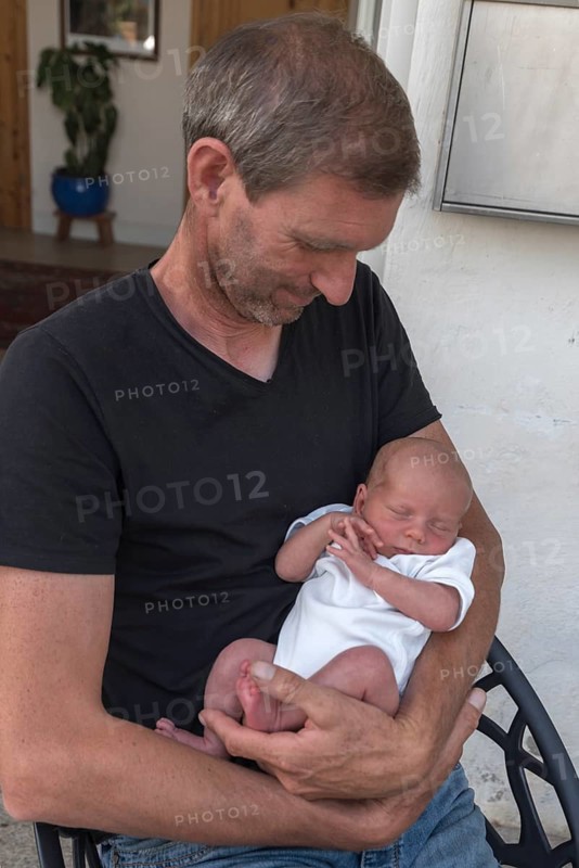 Young grandpa with his newborn grandson in his arms