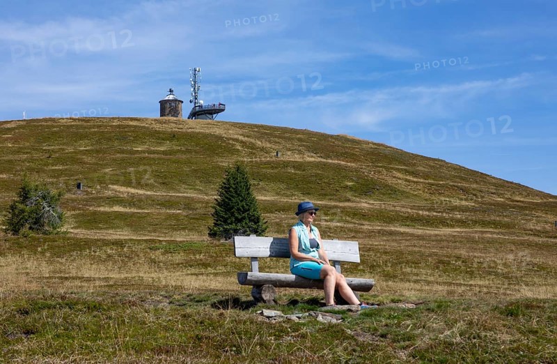 Hiker sitting on a bench on the Gerlitzen with view to the Kanzelhoehe